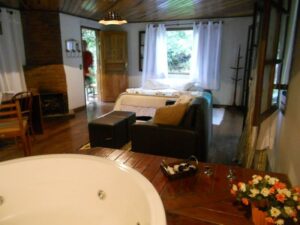 Banheira redonda e cama de casal e varanda ao lado na Pousada Jardim das &Aacute;guas