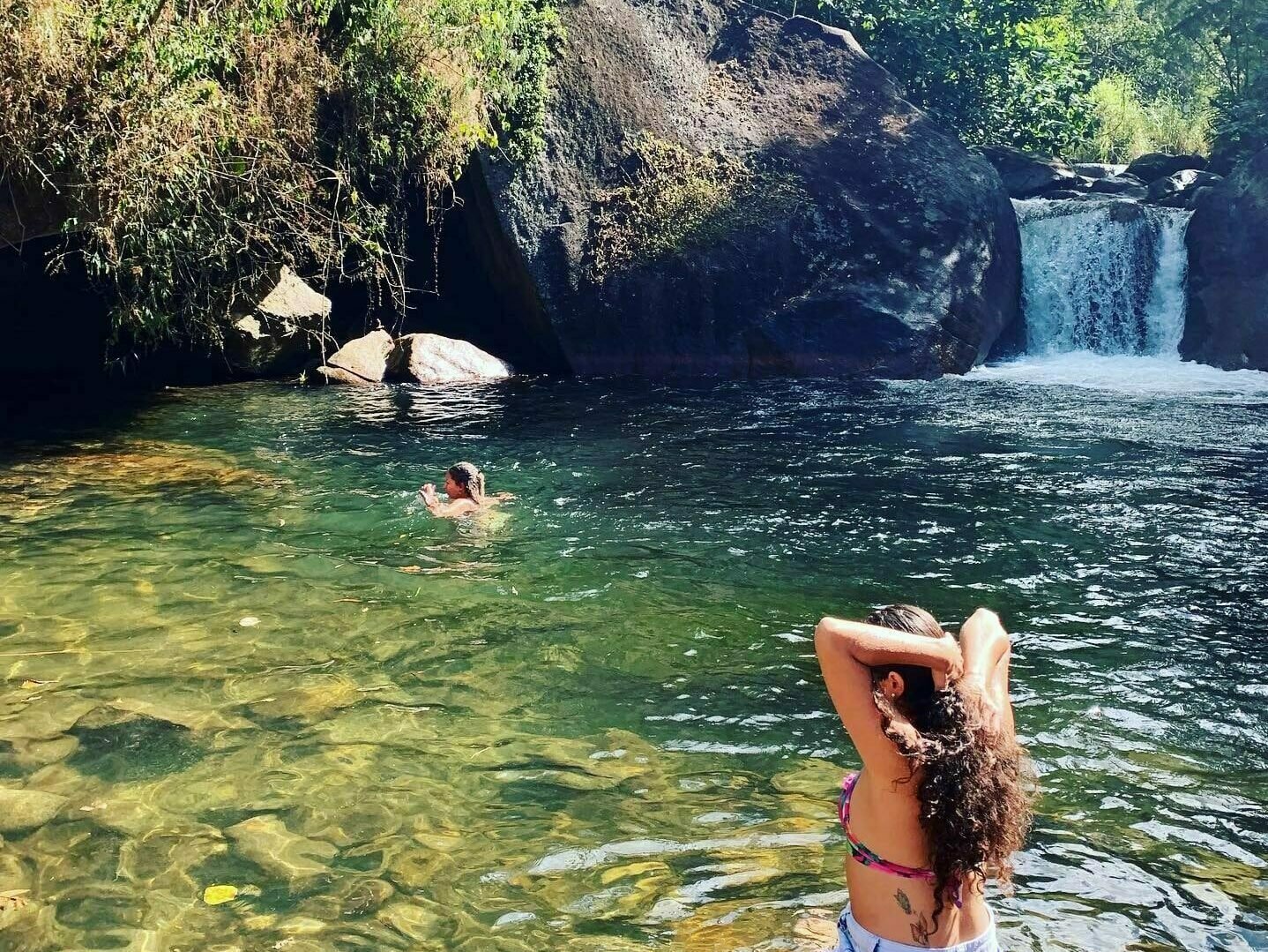 Moça se espreguiçando na cachoeira de Visconde de Mauá