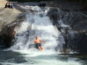 Homem escorregando na cachoeira em Visconde de Mauá
