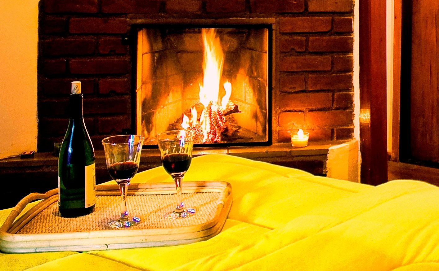 Lareira acessa com mesa ao lado com vinho e taças
