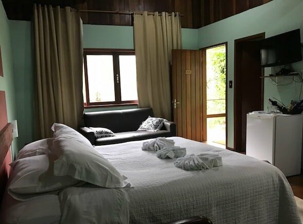 Cama de casal e sofá ao lado de vidraças