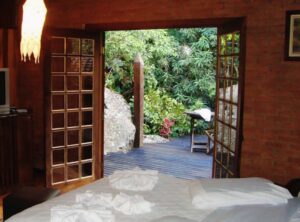 Quarto com cama de casal e janela aberta na Pousada Jardim das Águas