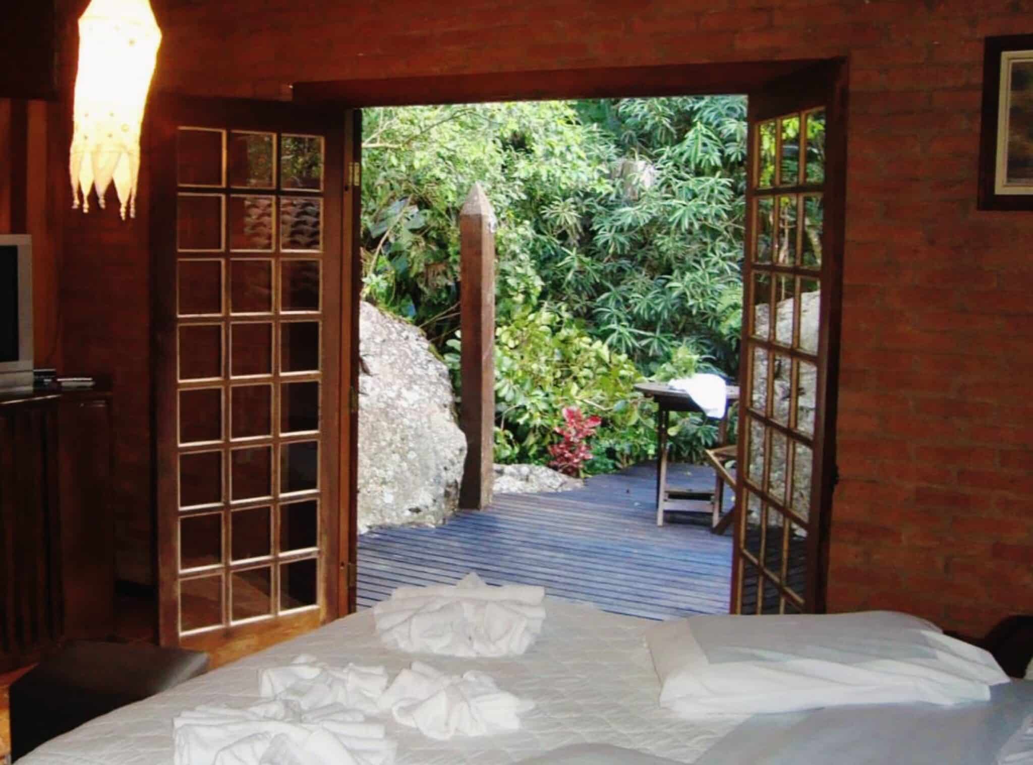 Quarto com cama de casal e janela aberta na Pousada Jardim das Águas