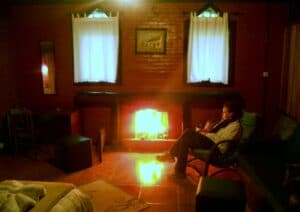 Lareira acessa com h&oacute;spede ao lado se aquecendo