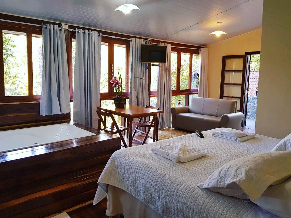 Cama de casal e sala do chalé na vila da Maromba