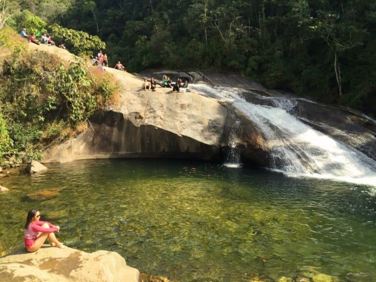 Mulher sentada na beira de uma cachoeira em Visconde de Maua RJ