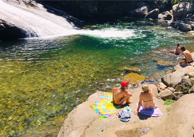 Duas mulhers sentadas na pedra da cachoeira em Visconde de Maua