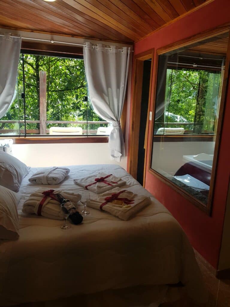 Cama de casal e janela aberta com vista para mata de Visconde de Mauá