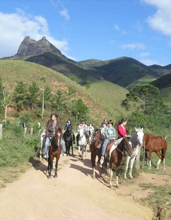 Grupo de pessoas andando a cavalo numa estrada de cascalho zona rural em Visconde de Maua.