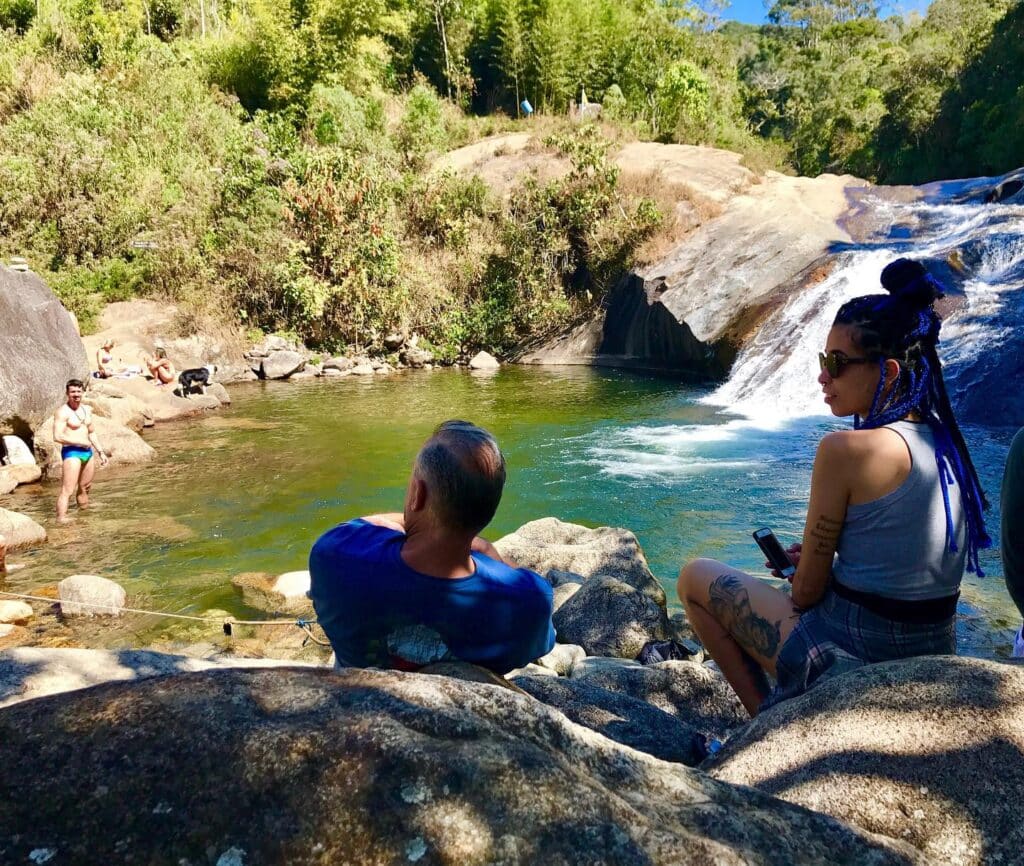 Casal tomando sol na pedra ás margens da cachoeira