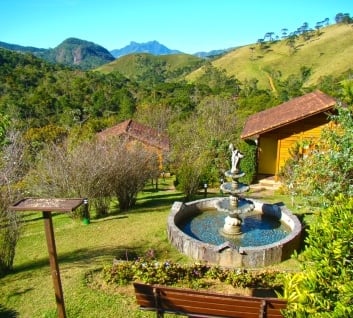 Chalé ao lado de uma fonte com colinas ao fundo