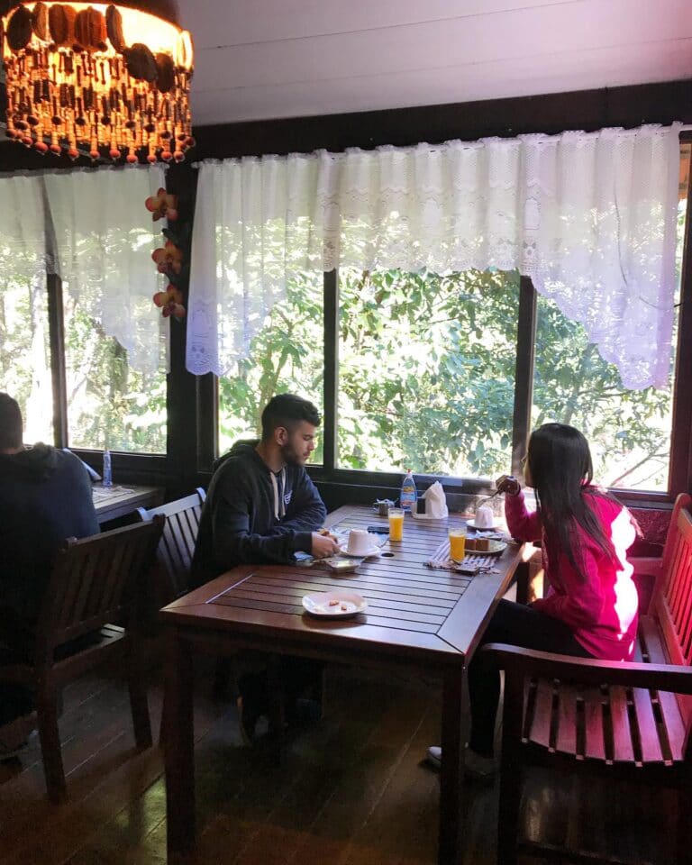 Casal em lados opostos da mesa com café da manhã