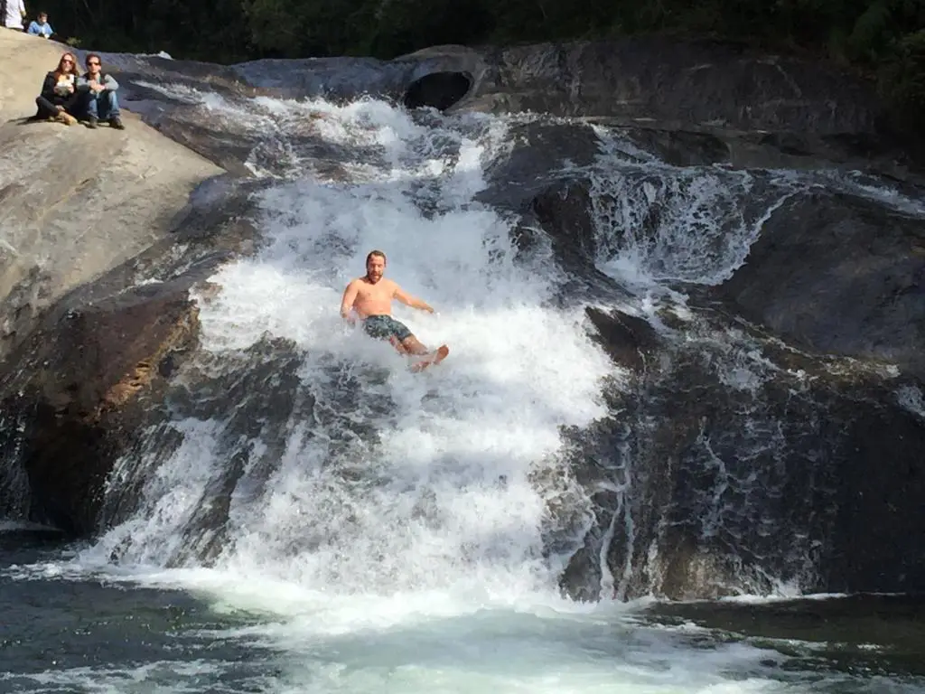 Homen deslizando no leito do rio da cachoeira do Escorrega