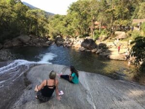 Mãe e filha sentadas na pedra ao lado do rio