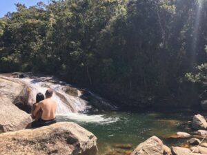 Casal sentado na pedra bem na margem da cachoeira do Escorrega