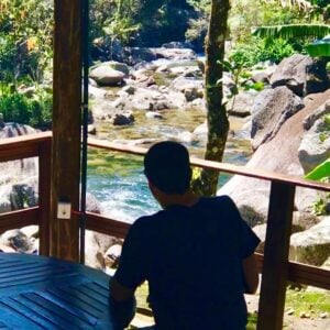 Vulto de homem sentado de costas e de frente a acachoeira em Visconde de Mauá