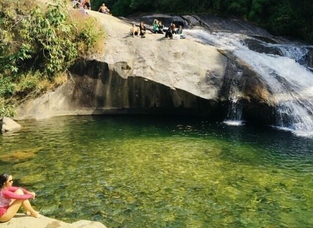 Garota sentada na pedra de um cachoeiras em Visconde de Mauá