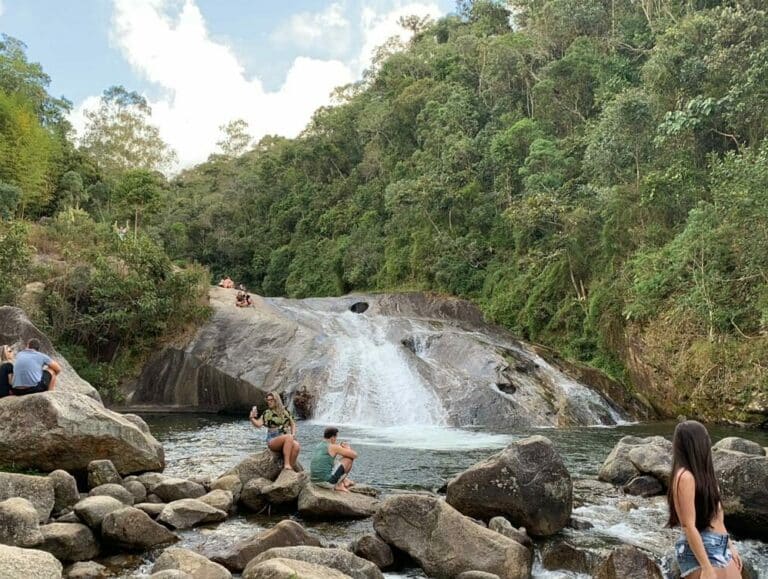 Casal sentado na pedra ao lado da cachoeira