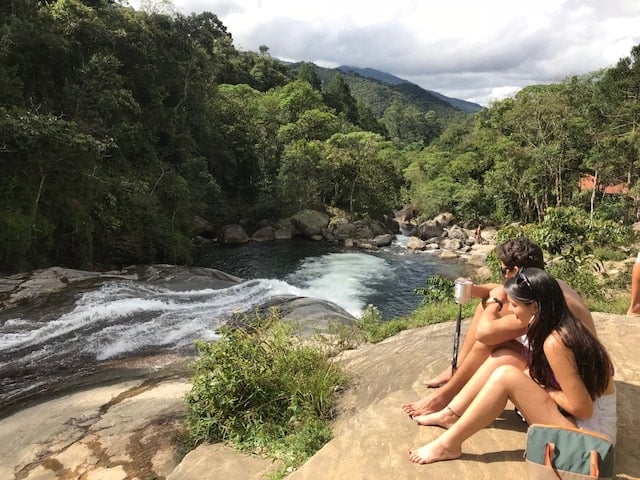 Casal sentado ao lado da cachoeira