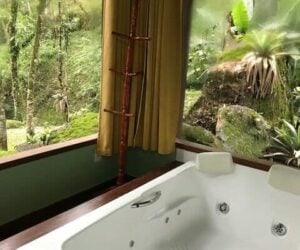 Banheira com vidra&ccedil;as com vista do jardim da pousada