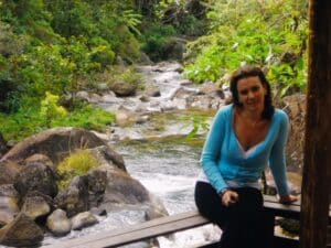 Mulher sentada na cerca e rio de Visconde de Mau&aacute; ao fundo