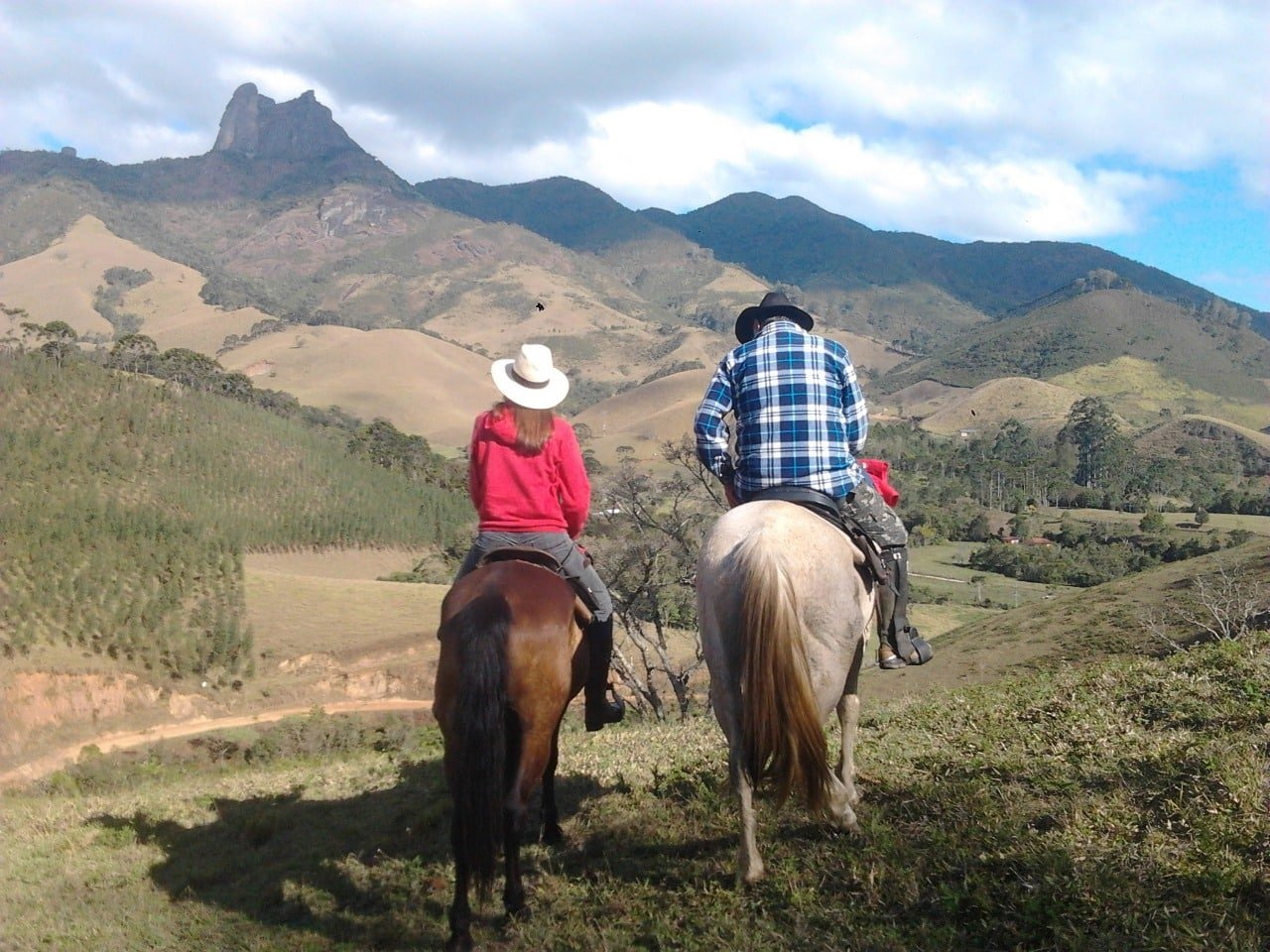 Casal em em cima de cavalos e montanhas ao fundo em Visconde de Mauá