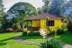 Chalé amarelo em meio ao jardim na vila de Maringá