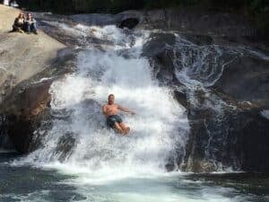 Homem descendo a cachoeira do Escorrega , um tobogá natural em Visconde de Maua