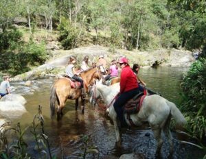 Pessoas a cavalo atravessando o rio