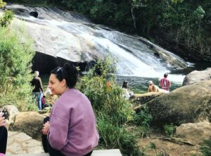 Mulher sentada com a principal cachoeira de Visconde de Mauá ao fundo