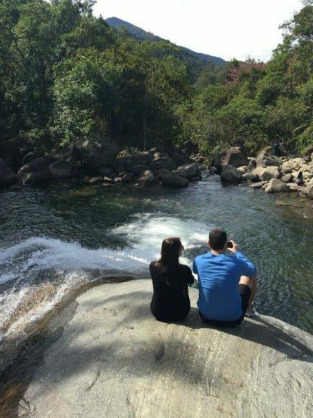 Casal sentado olhando a vista da cachoeira em visconde de maua