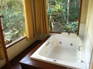Banheira com janelas com vista para o jardim da pousada em Maua RJ
