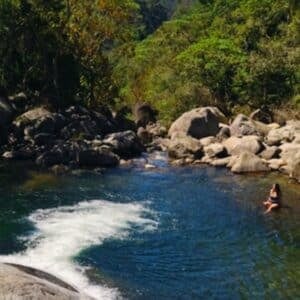 Garota sentada em uma pedra submersa na cachoeira em Maromba